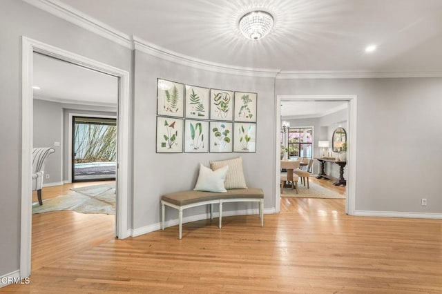 corridor featuring crown molding, light wood-style flooring, baseboards, and a chandelier
