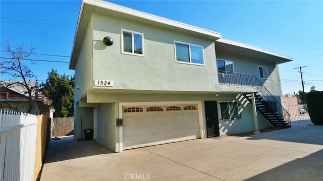 view of front facade featuring fence, stairs, an attached garage, stucco siding, and concrete driveway