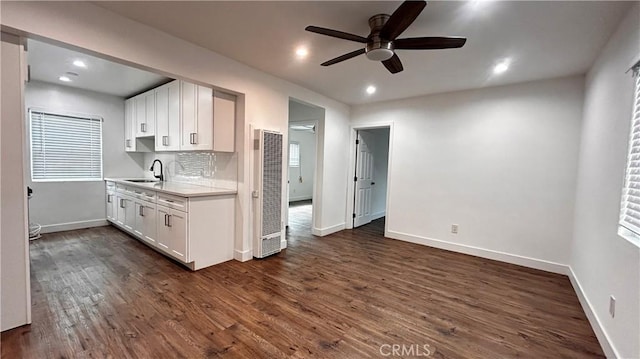 kitchen featuring a sink, white cabinets, ceiling fan, and a heating unit