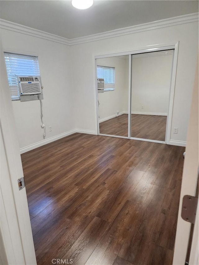unfurnished bedroom with crown molding, baseboards, wood finished floors, and a closet