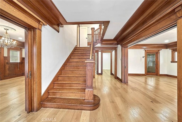 staircase with crown molding, wood-type flooring, and a notable chandelier