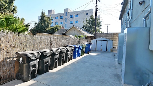 view of patio with fence, a storage unit, and an outdoor structure