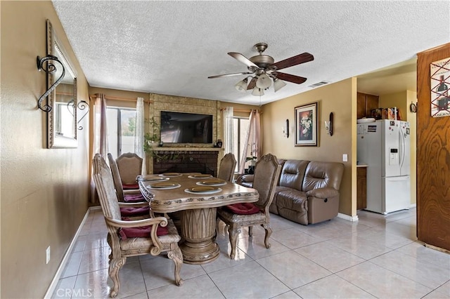 dining room featuring a textured ceiling, baseboards, light tile patterned flooring, and ceiling fan