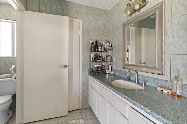 bathroom with toilet, tile patterned floors, tile walls, and vanity