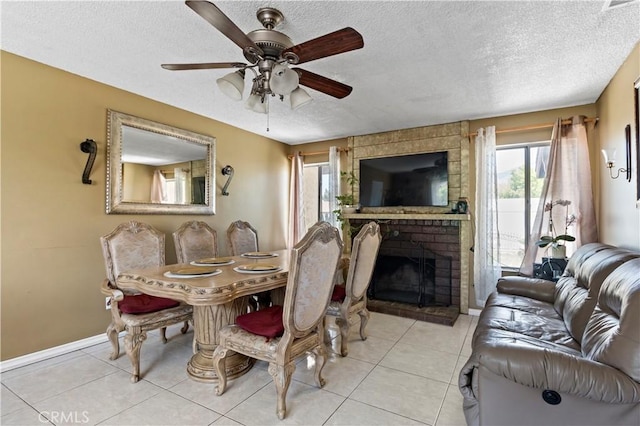 dining room with tile patterned flooring, a ceiling fan, a textured ceiling, and a fireplace