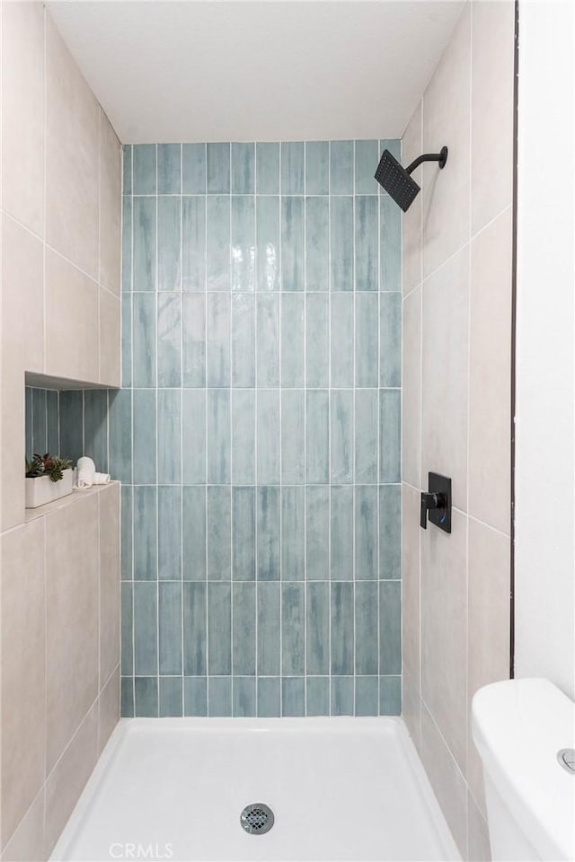 bathroom with toilet and tiled shower