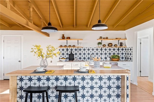 kitchen with backsplash, open shelves, beam ceiling, white cabinets, and light wood-style floors