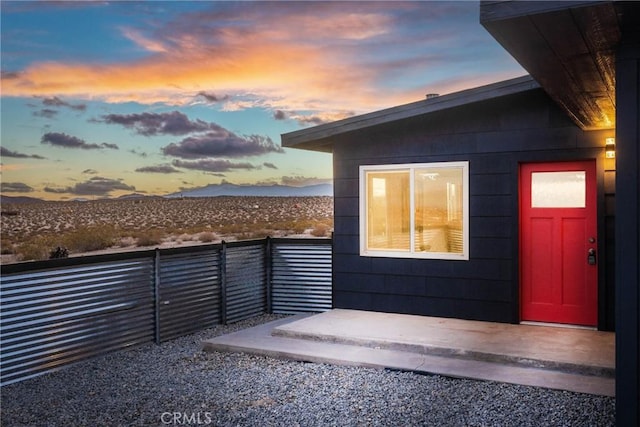 exterior entry at dusk featuring a mountain view and fence