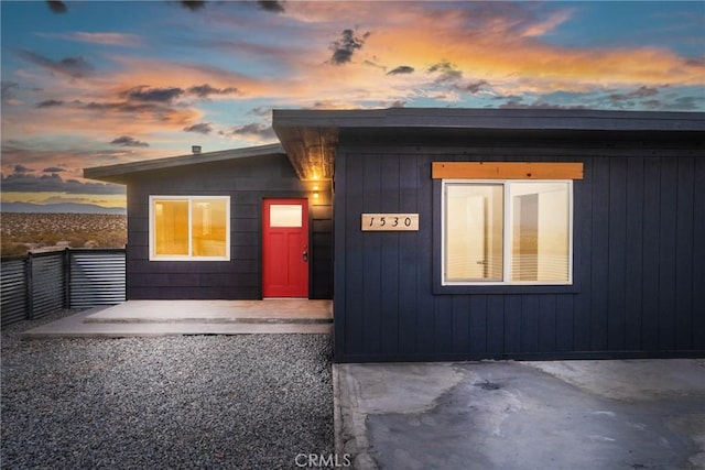 view of exterior entry featuring a patio and fence