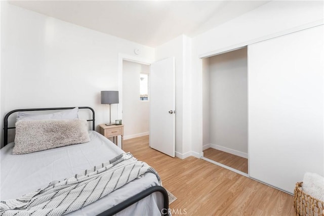bedroom with a closet, baseboards, and light wood-type flooring