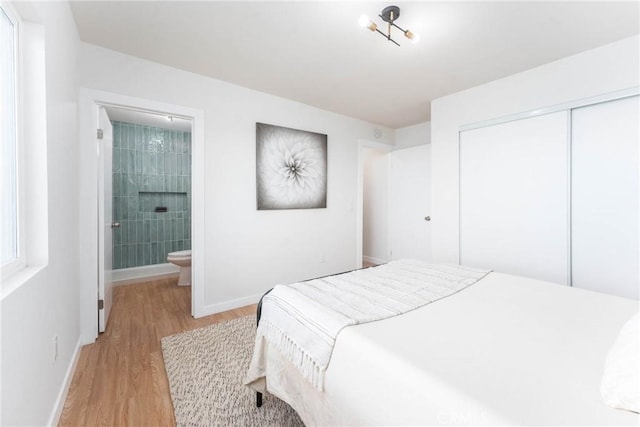 bedroom with a closet, light wood finished floors, ensuite bathroom, and baseboards