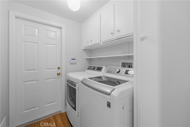 washroom with cabinet space, independent washer and dryer, and dark wood-type flooring