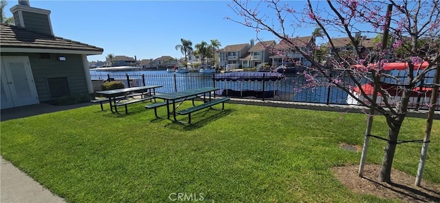 view of yard featuring a water view, fence, and a residential view