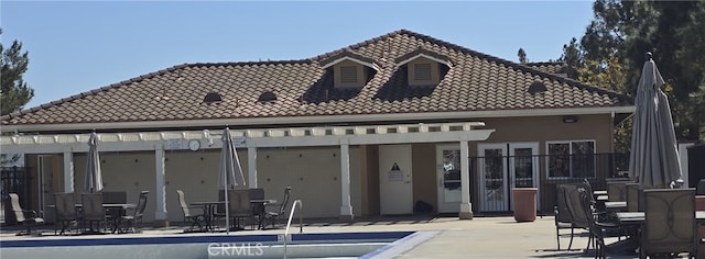 rear view of house with a tiled roof, a community pool, a patio area, and stucco siding