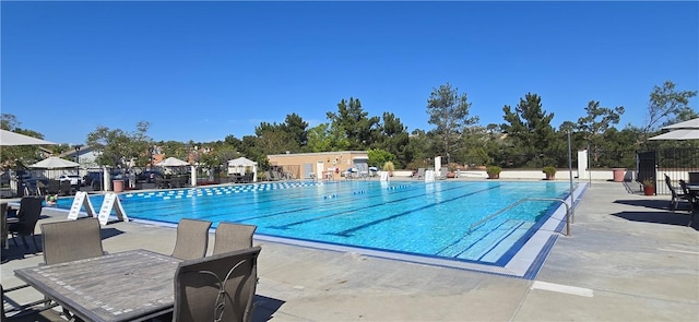 pool featuring outdoor dining area, a patio area, and fence