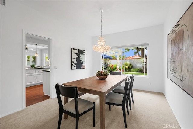 dining area with plenty of natural light, light carpet, visible vents, and a chandelier
