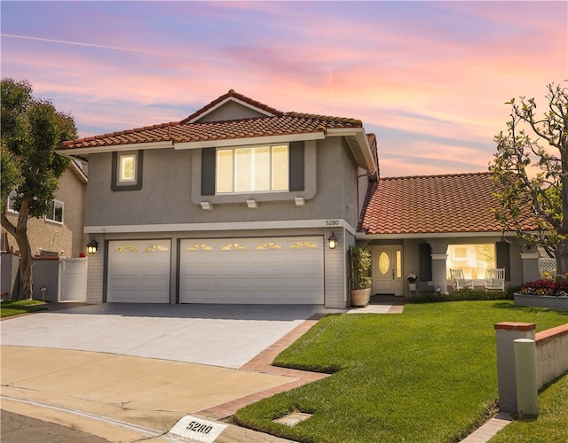 traditional-style house with a tiled roof, driveway, a yard, an attached garage, and stucco siding
