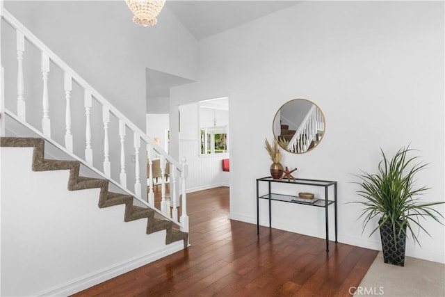 staircase with baseboards, wood finished floors, and a notable chandelier