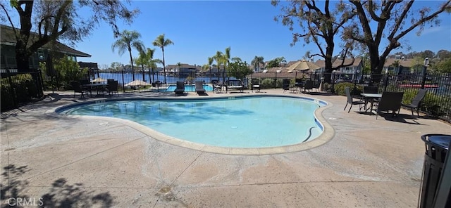 community pool with a patio area and fence