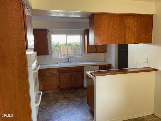 451 Redwood St, Oxnard, CA 93033 - kitchen featuring a sink, brown cabinetry, dishwasher, backsplash, and tile countertops