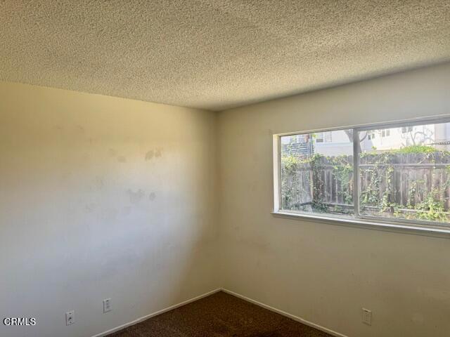 451 Redwood St, Oxnard, CA 93033 - unfurnished room featuring a textured ceiling, dark carpet, and baseboards