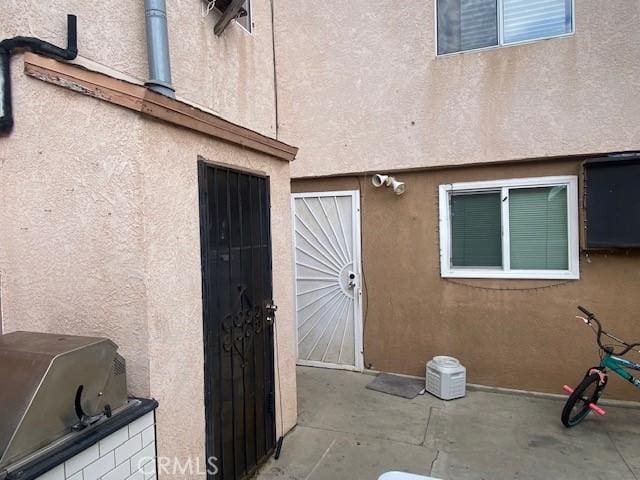 property entrance with stucco siding and a patio area