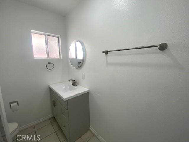 bathroom featuring vanity, baseboards, tile patterned floors, and toilet