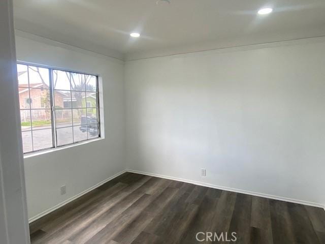 spare room featuring recessed lighting, baseboards, and dark wood-type flooring