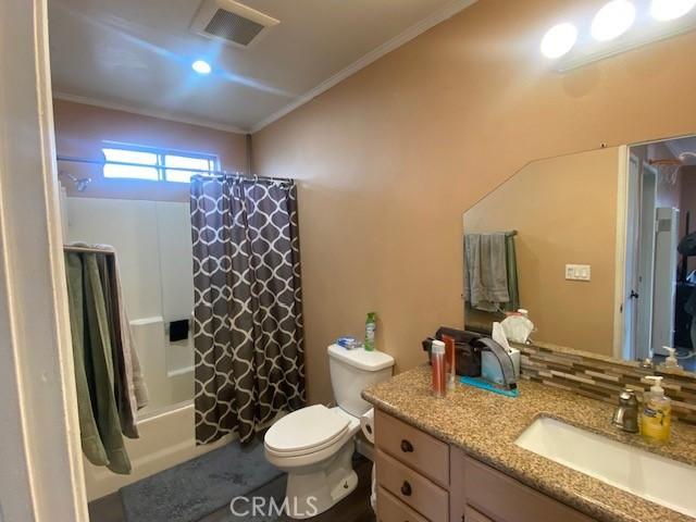 full bathroom featuring shower / bath combo, vanity, toilet, visible vents, and ornamental molding