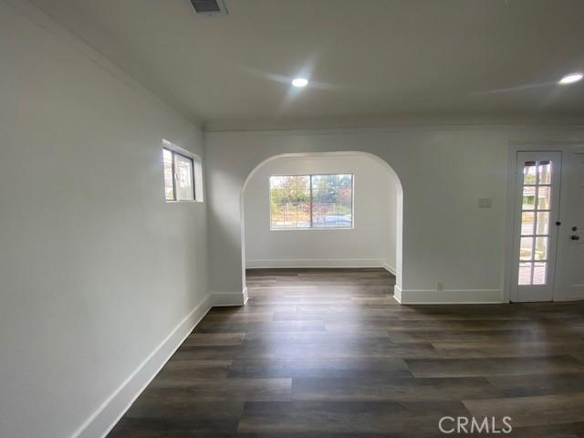 unfurnished room featuring arched walkways, baseboards, and recessed lighting