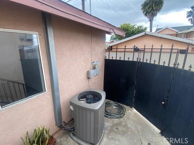 exterior space with cooling unit, stucco siding, and fence