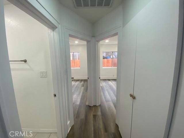 hall featuring baseboards, wood finished floors, and visible vents