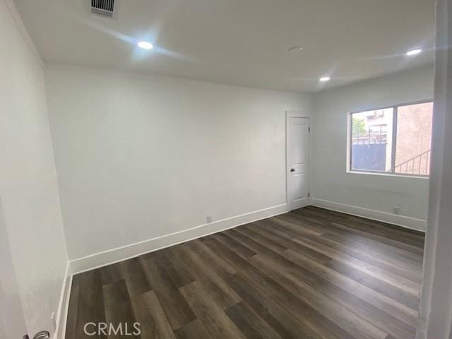 unfurnished room with visible vents, recessed lighting, baseboards, and dark wood finished floors