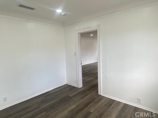 unfurnished room featuring dark wood-style flooring, visible vents, baseboards, ornamental molding, and recessed lighting