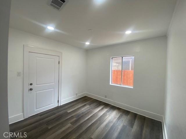 spare room featuring recessed lighting, baseboards, and dark wood finished floors