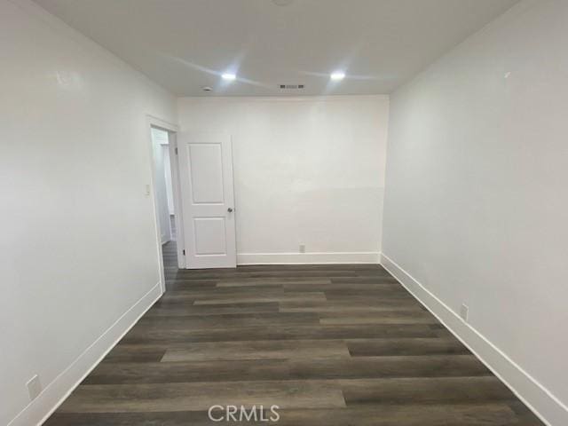unfurnished room featuring baseboards, visible vents, and wood finished floors