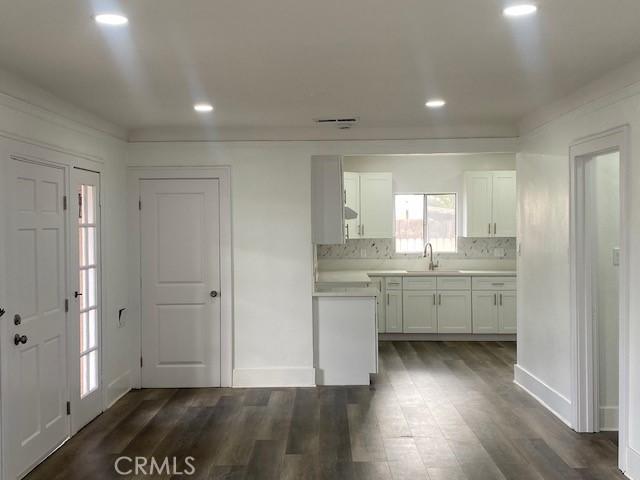 kitchen featuring a sink, light countertops, dark wood finished floors, white cabinetry, and recessed lighting
