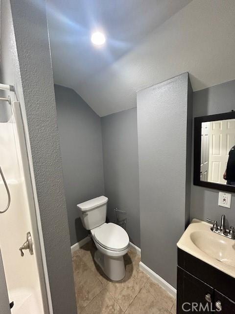full bath with vanity, a shower, toilet, tile patterned floors, and vaulted ceiling