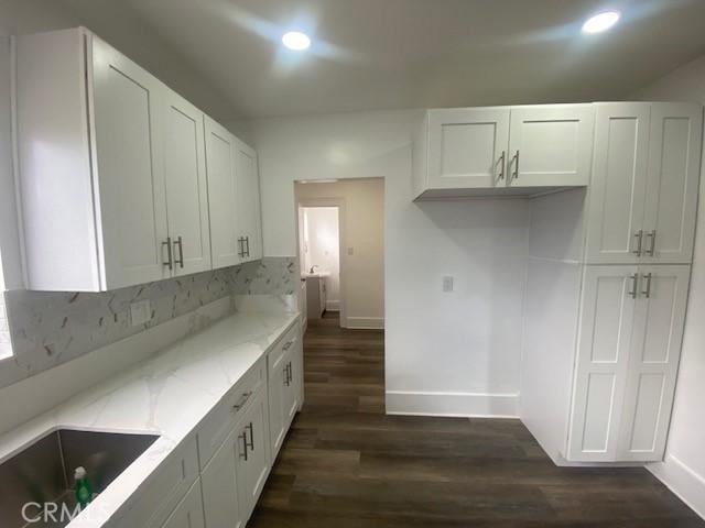 kitchen featuring baseboards, white cabinetry, and light stone countertops
