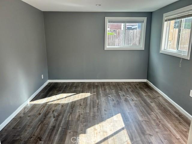 spare room featuring baseboards, wood finished floors, and a wealth of natural light