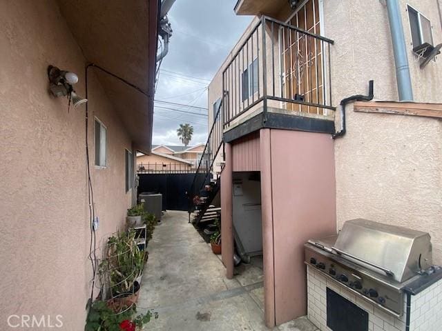 view of home's exterior featuring central air condition unit, stairs, stucco siding, and exterior kitchen