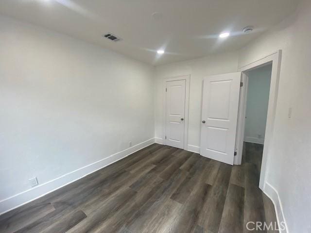 unfurnished room featuring recessed lighting, baseboards, visible vents, and dark wood-style floors