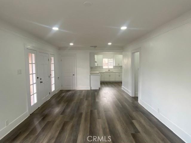 unfurnished living room with recessed lighting, baseboards, and dark wood finished floors
