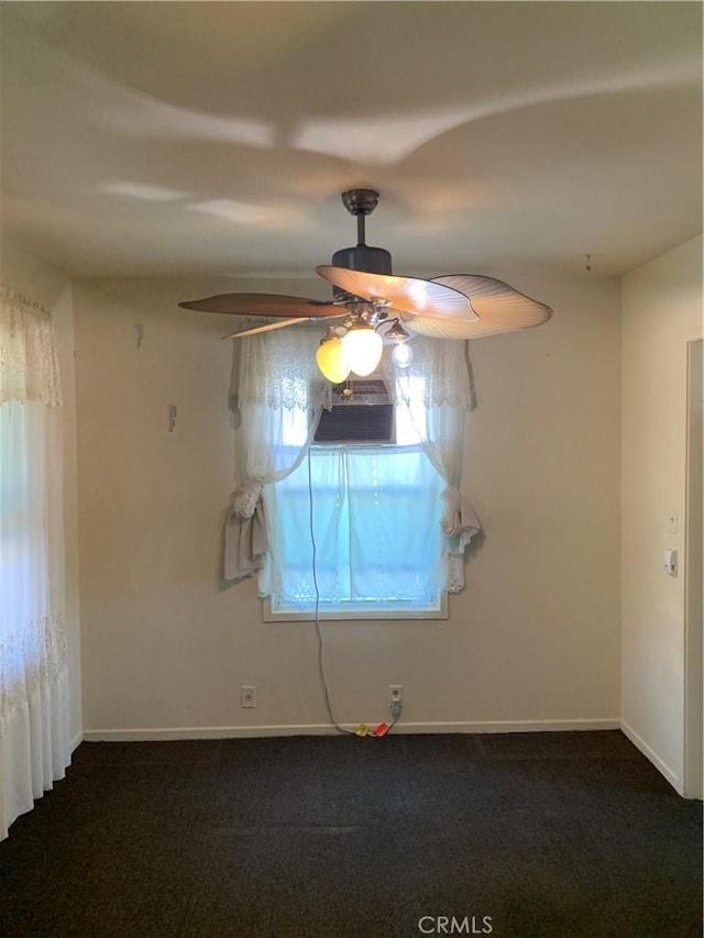 spare room featuring dark colored carpet, a ceiling fan, and baseboards