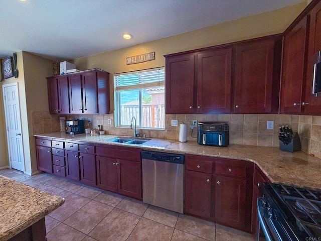 kitchen featuring tasteful backsplash, stainless steel dishwasher, a sink, light tile patterned floors, and range with gas stovetop