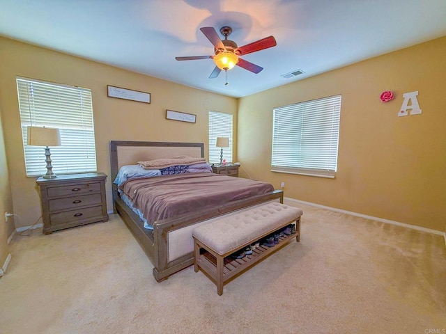 carpeted bedroom featuring baseboards, a ceiling fan, and visible vents