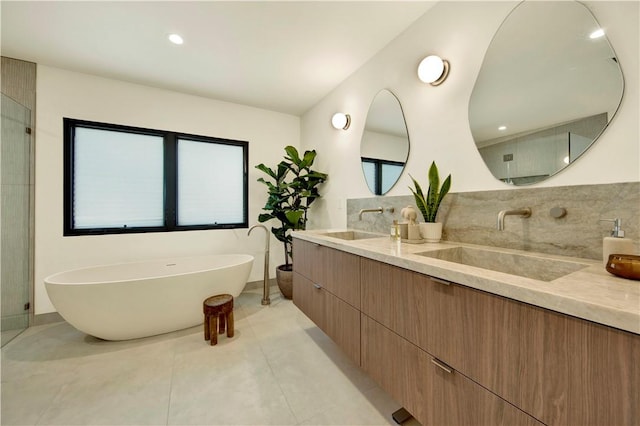full bathroom with double vanity, a sink, plenty of natural light, and a soaking tub