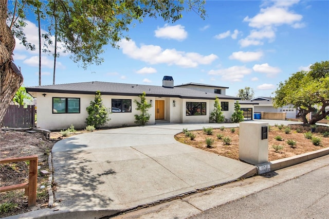 single story home featuring concrete driveway, fence, and stucco siding