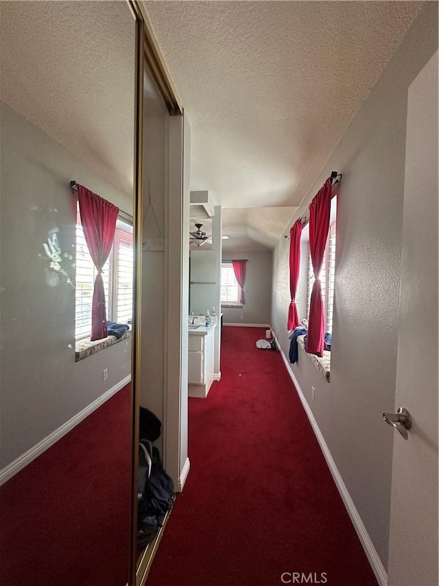 21205 Serra Unit 42, Lake Forest, CA 92630 - corridor featuring a textured ceiling, vaulted ceiling, baseboards, and carpet floors