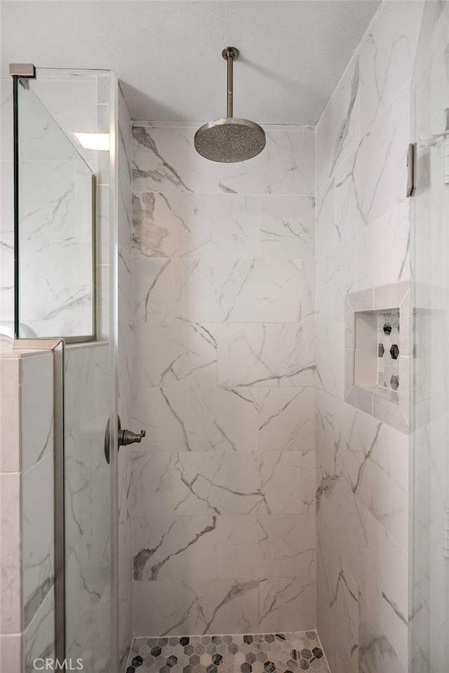bathroom with a marble finish shower and a textured ceiling